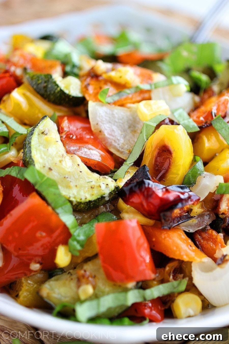 Easy Roasted Summer Vegetables – A serving dish filled with colorful roasted vegetables topped with melted cheese and fresh basil.