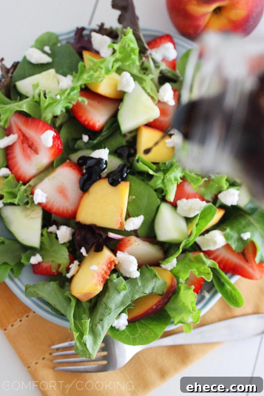 Summer Strawberry-Peach Salad with Goat Cheese – Close-up of creamy goat cheese crumbles artfully placed over fresh fruit and greens, highlighting the salad's texture.