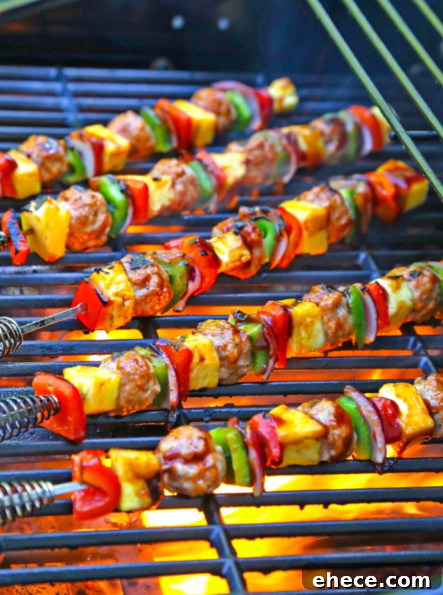 Close-up of grilled sausage, veggie, and pineapple skewers on the grill, showing char marks.
