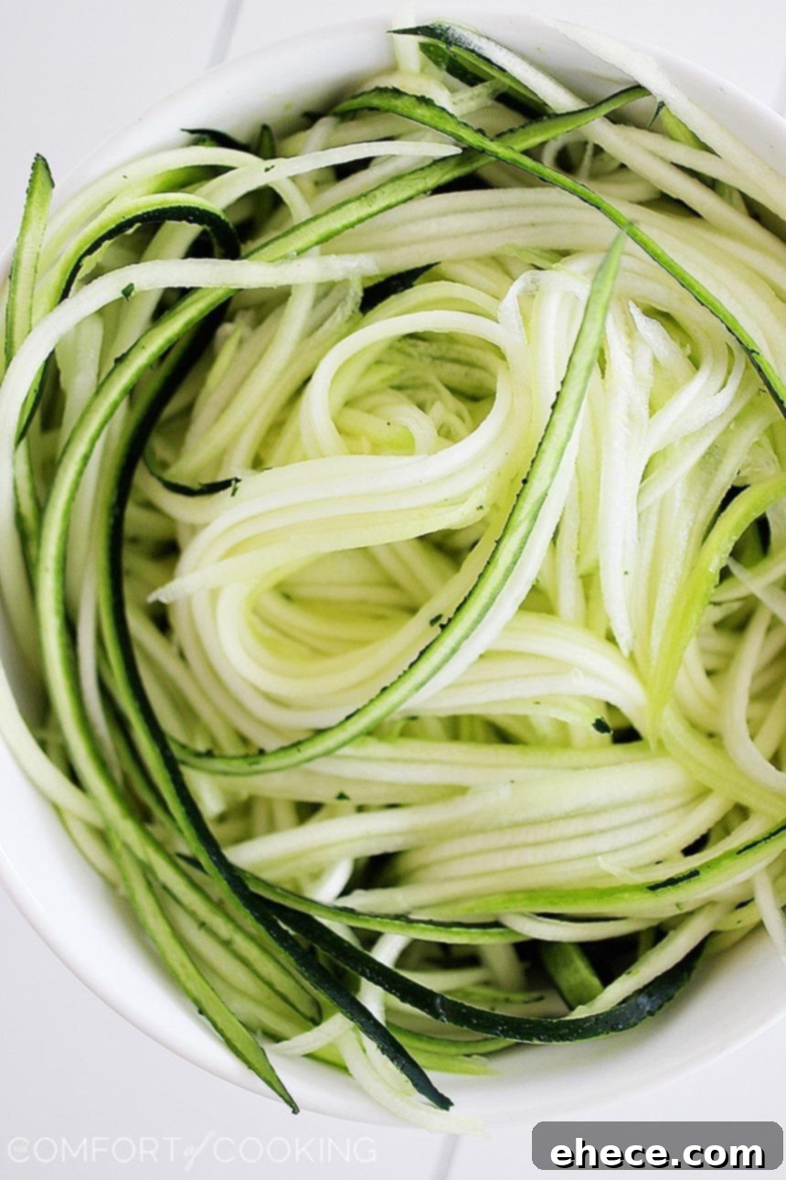 Delicious Zucchini Noodles coated in a creamy lemon sauce, garnished with fresh tomatoes - A perfect healthy meal.