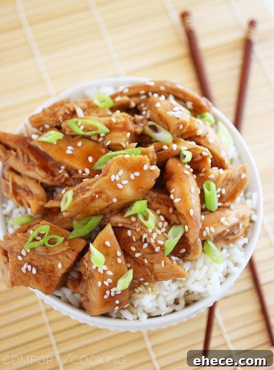 Slow Cooker Teriyaki Chicken served over white rice with a sprinkle of sesame seeds and chopped green onions.