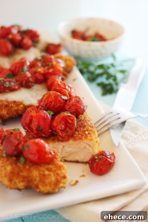 Side view of Crispy Parmesan Chicken and perfectly roasted tomatoes