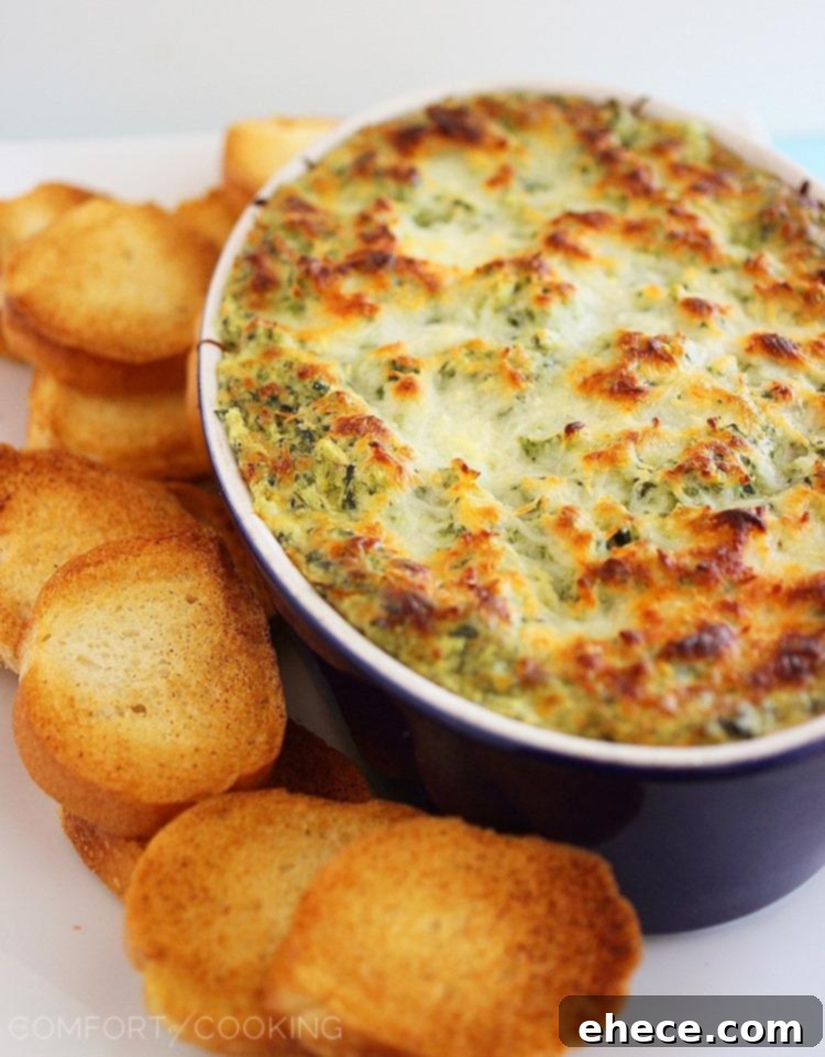 Hot Cheesy Spinach-Artichoke Dip served with toasted baguette slices and fresh garnishes, ready for a party.