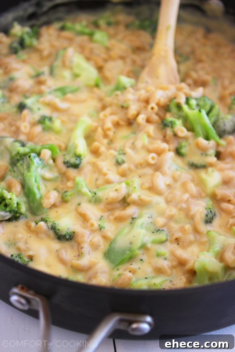 Close-up of a serving of baked broccoli mac and cheese, showing melted cheese and tender broccoli florets.