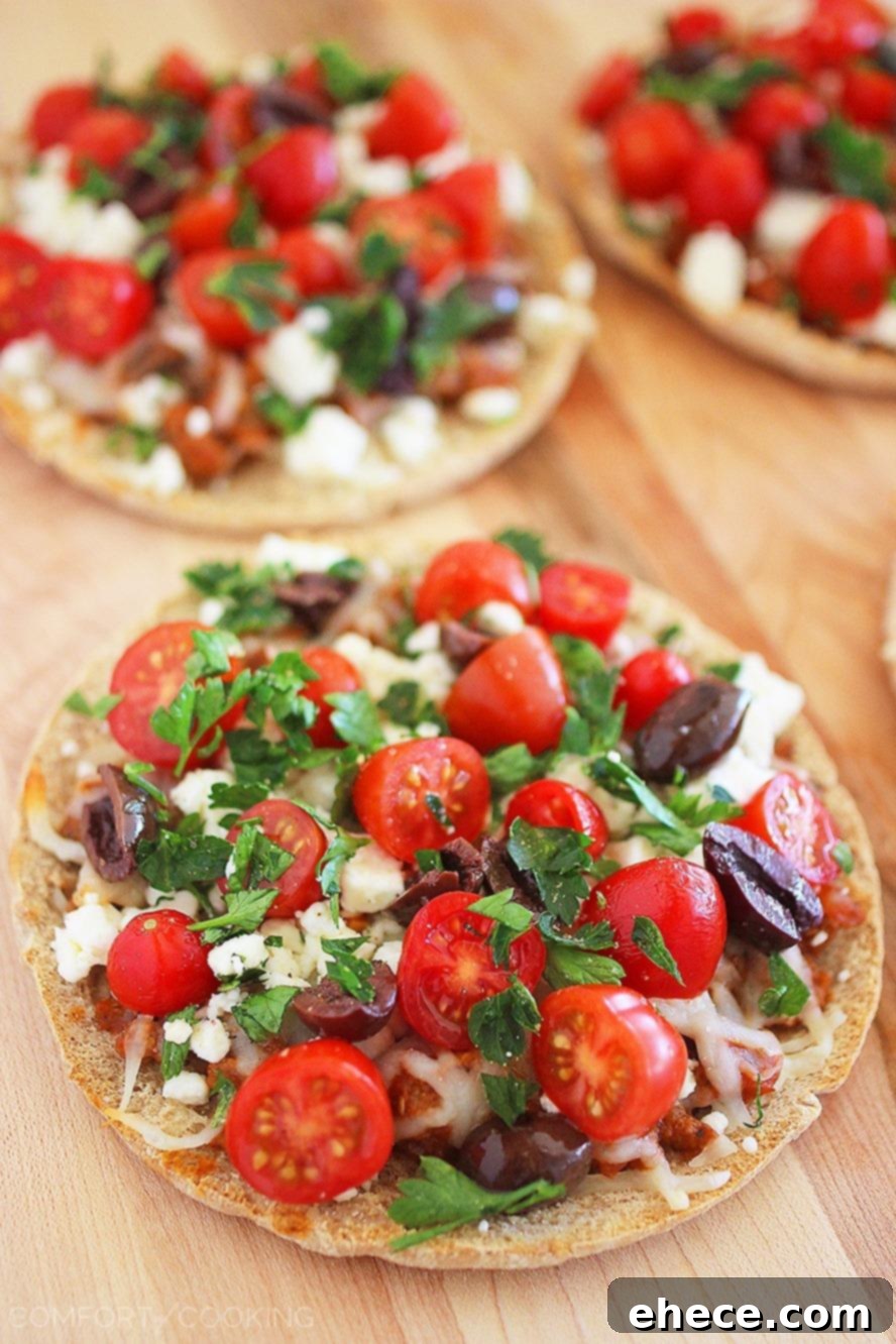Greek Pita Pizzas – Super easy & full of Mediterranean flavor. Creamy feta, fresh tomatoes and a quick homemade tomato sauce make them mouthwatering!