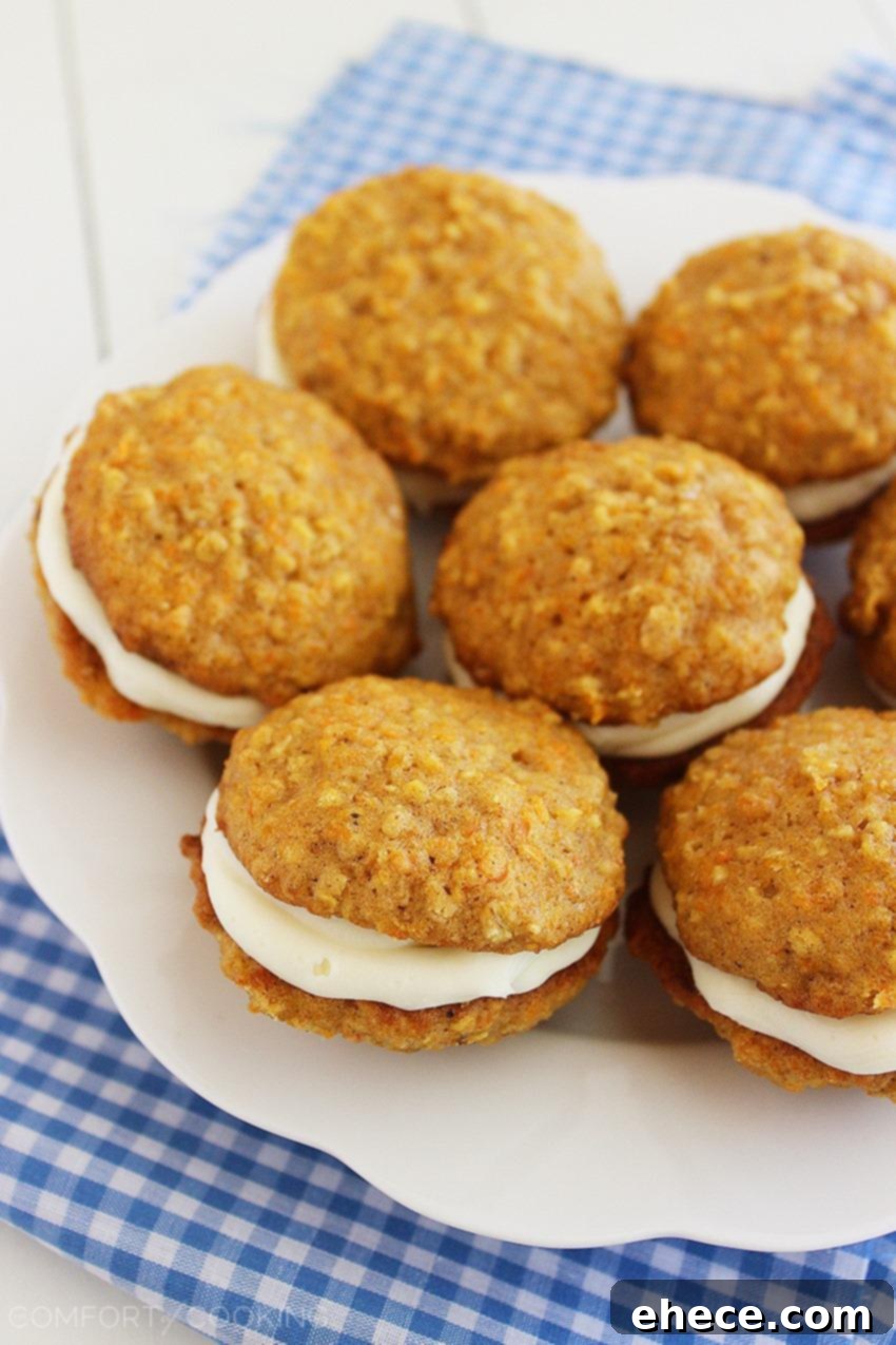 Three Soft Carrot Cake Sandwich Cookies displayed on a wooden surface, highlighting the delicious texture and inviting cream cheese filling.