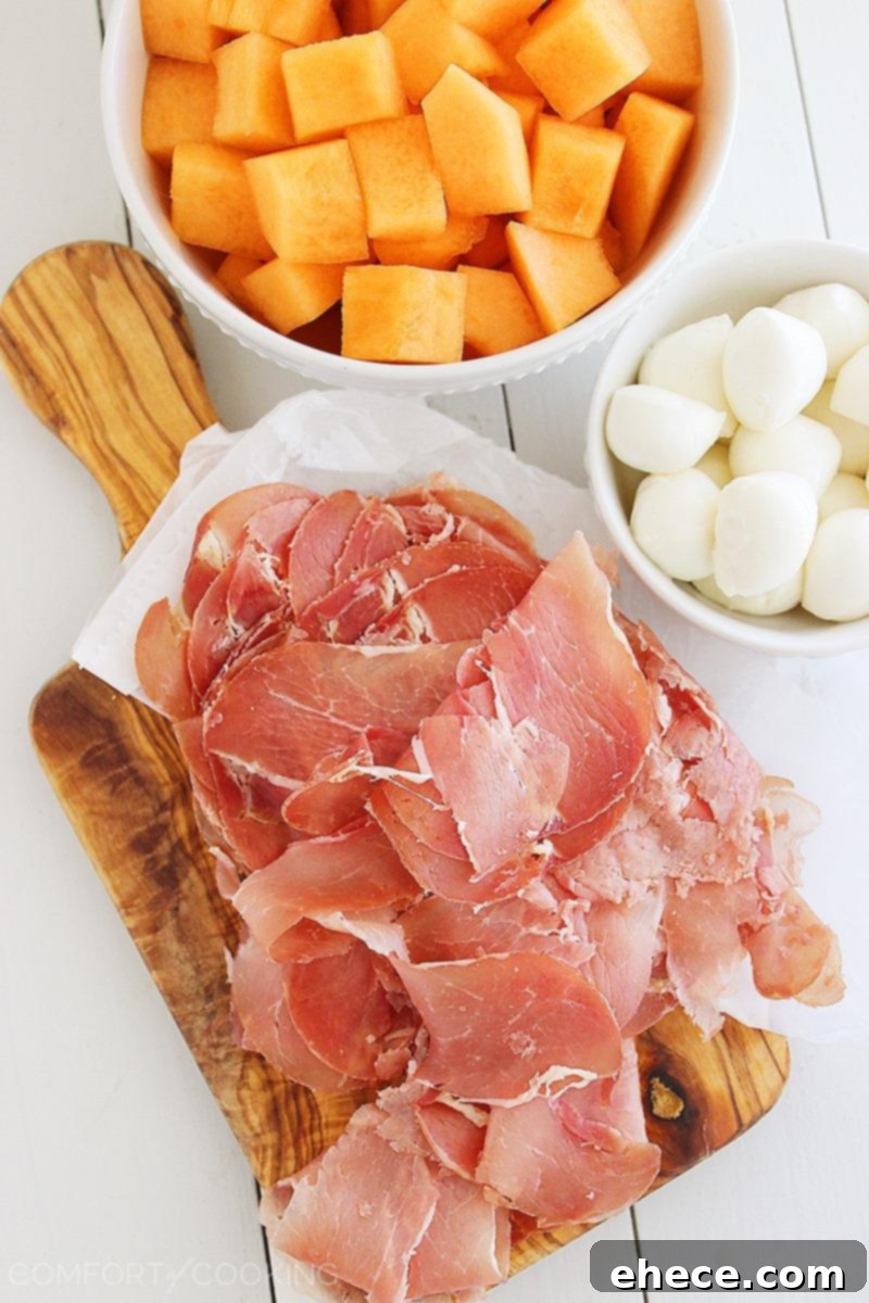 Close-up of Melon, Prosciutto, and Mozzarella Skewers with fresh basil garnish, ready for serving at a party. A delightful combination of Italian flavors. | thecomfortofcooking.com