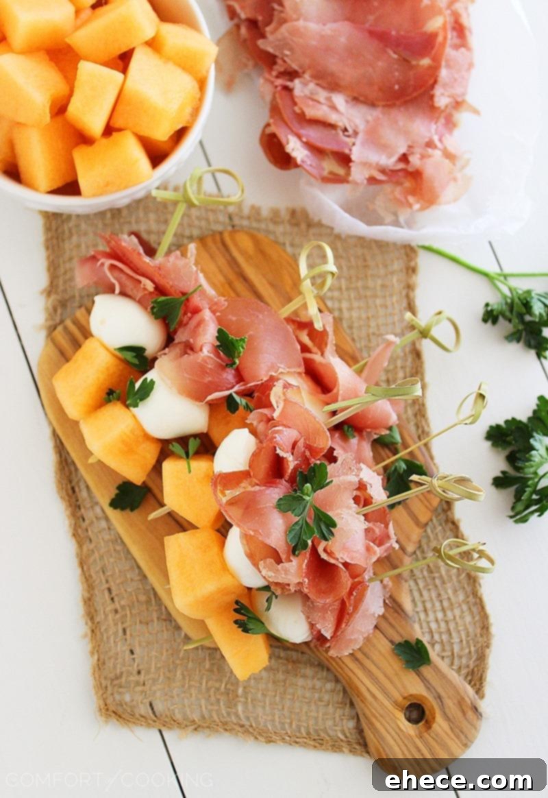 Three prepared Melon, Prosciutto, and Mozzarella Skewers on a white plate, showcasing the vibrant colors and fresh ingredients. Easy gourmet finger food. | thecomfortofcooking.com