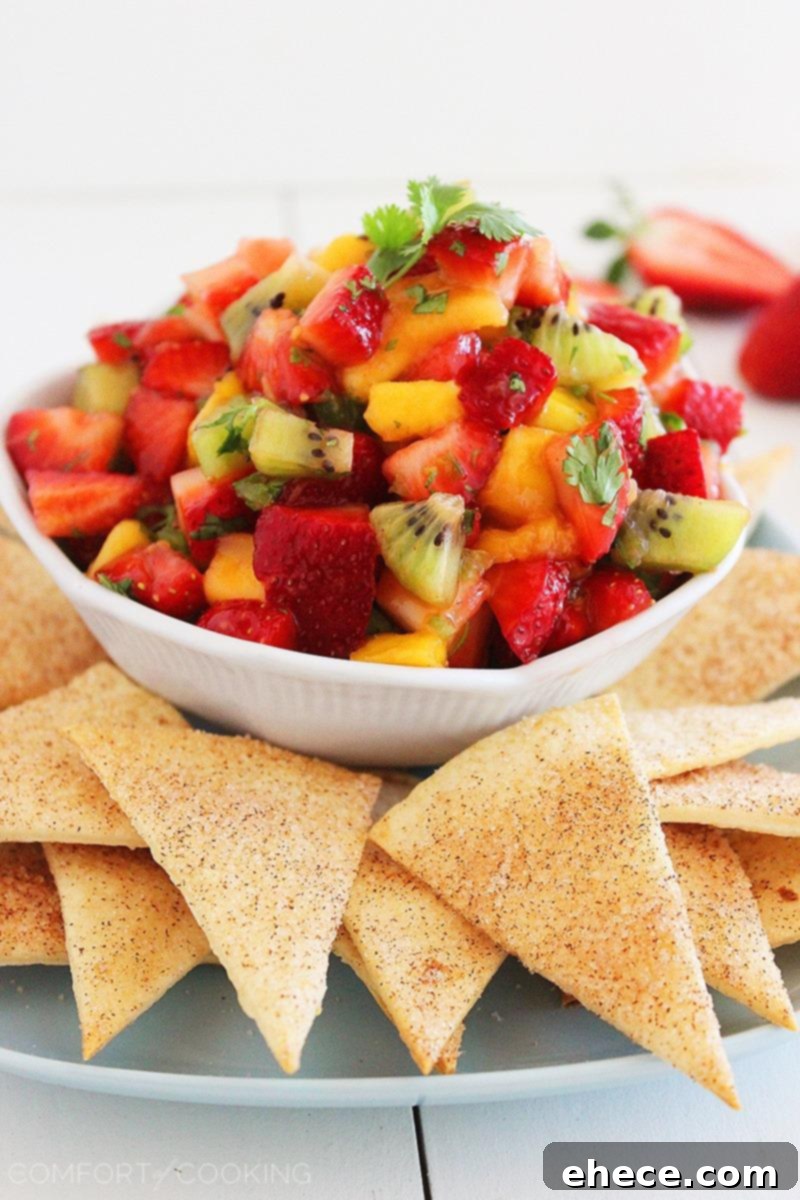 An overhead shot of the full spread: Strawberry Mango Salsa in a bowl surrounded by golden Cinnamon-Sugar Tortilla Chips.