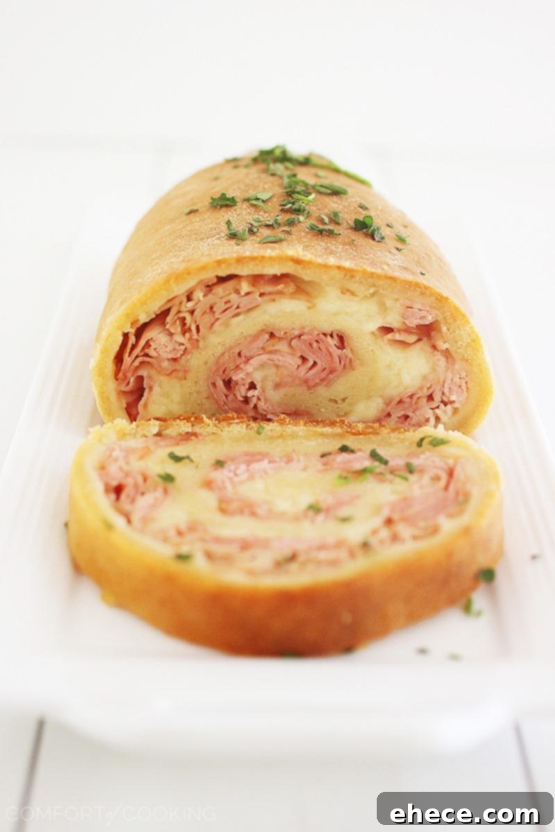 Three-Ingredient Baked Ham and Cheese Swirls 4 Another perspective of uncooked Ham and Cheese Rollups on a baking sheet, showcasing the careful rolling and sealing technique.