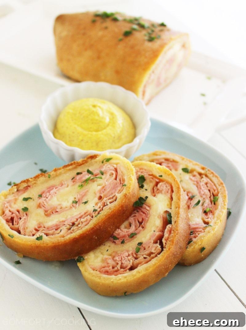 Three-Ingredient Baked Ham and Cheese Swirls 6 Close-up of a single slice of Ham and Cheese Rollup, showing the perfectly melted cheese and savory ham filling.