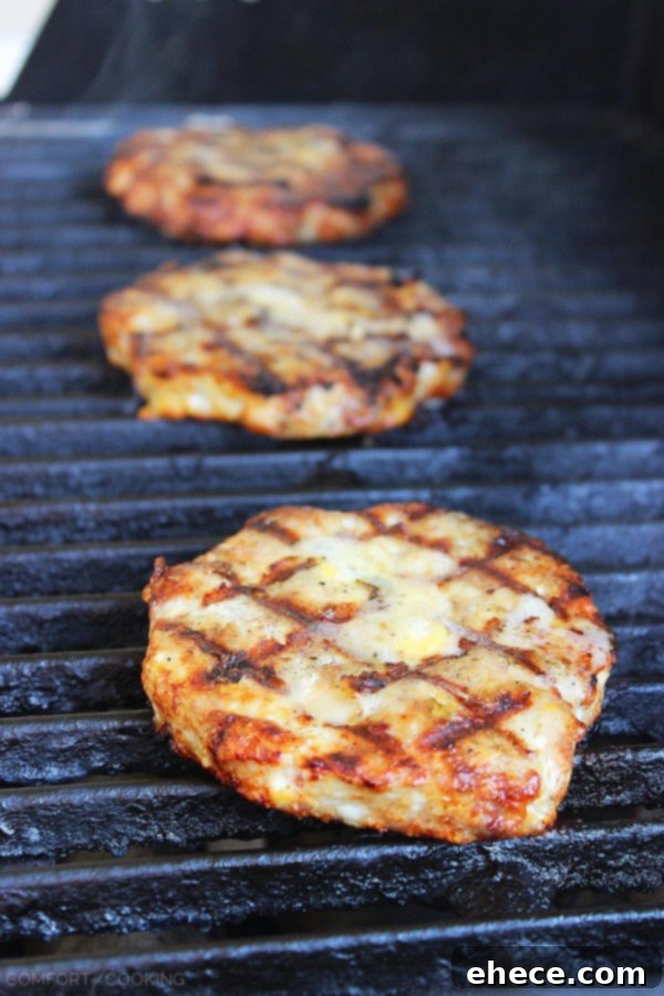 Close-up of a perfectly grilled BBQ Bacon-Cheddar Chicken Burger, ready to be assembled with fresh toppings. | thecomfortofcooking.com