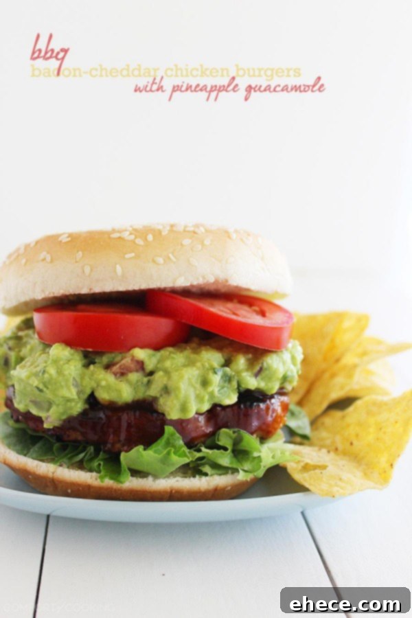 Two mouthwatering BBQ Bacon-Cheddar Chicken Burgers, showcasing the juicy patties and vibrant pineapple guacamole. | thecomfortofcooking.com