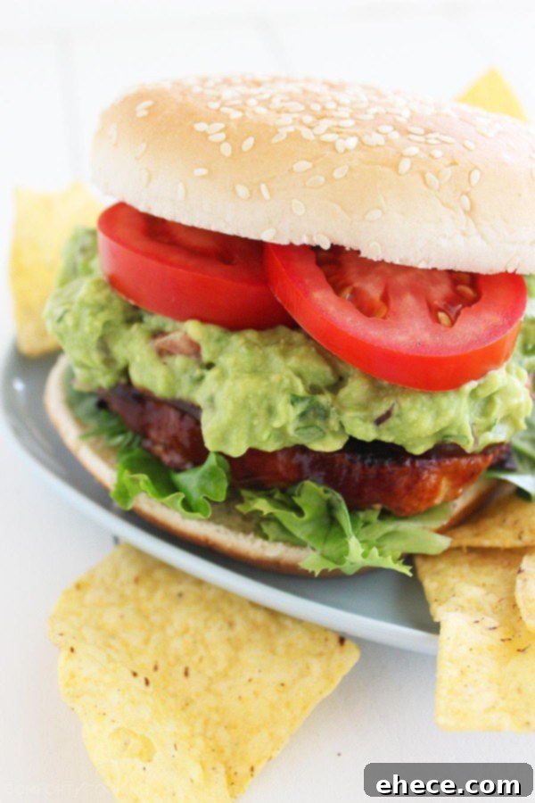 Assembled BBQ Bacon-Cheddar Chicken Burger with a generous dollop of fresh pineapple guacamole. | thecomfortofcooking.com
