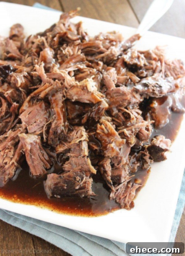 Platter of tender, succulent shredded slow cooker balsamic glazed roast beef, ready for serving.