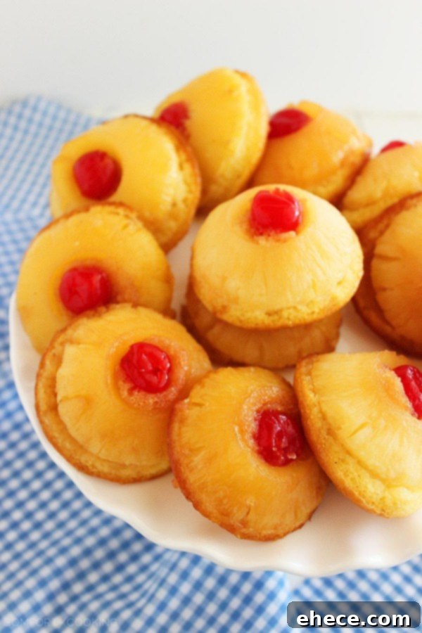 Batch of freshly baked Mini Pineapple Upside Down Cakes cooling on a wire rack, showing their golden crust and juicy pineapple topping. Ideal for summer parties. | thecomfortofcooking.com