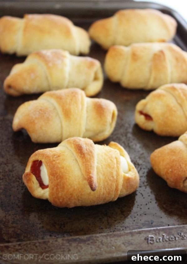 Pepperoni Pizza Crescent Bites 4 Freshly baked Pepperoni Pizza Crescent Rollups on a baking sheet, showcasing their golden crust and savory filling, perfect for any gathering.
