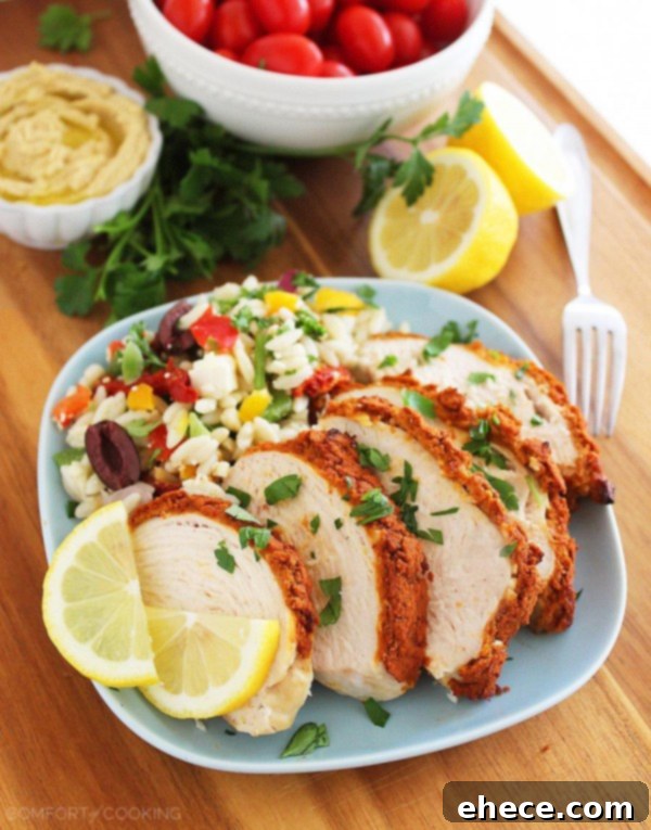 Baked Hummus-Crusted Lemon Chicken, topped with a creamy, crispy hummus crust and a squeeze of fresh lemon. Served alongside a fresh salad for a healthy weeknight meal.