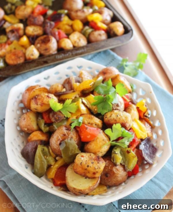 Close-up of vibrant roasted chicken sausage, bell peppers, and golden potatoes on a baking sheet, ready to serve.