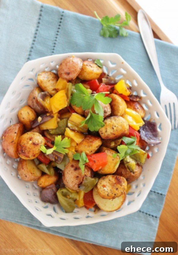 Beautifully arranged roasted chicken sausage, potatoes, and peppers on a white plate, garnished with fresh parsley.