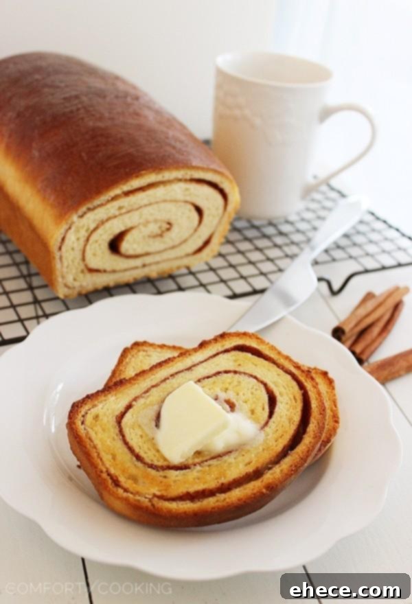 A beautifully sliced loaf of Soft Cinnamon Swirl Bread, showcasing its intricate cinnamon ribbons and golden crust, perfect for breakfast with coffee.