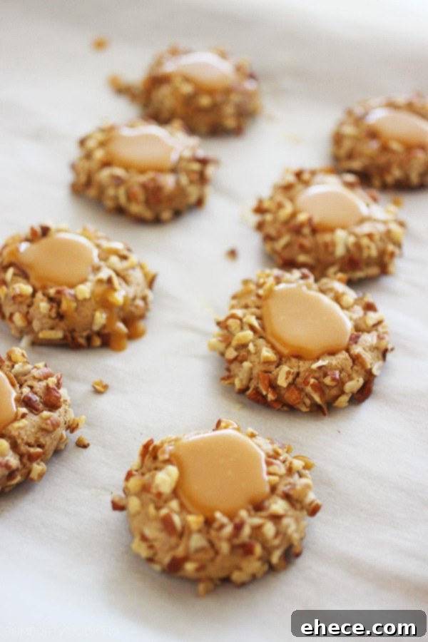 Close-up of golden-brown Caramel Spice Thumbprint Cookies on a baking sheet, showcasing their soft texture and potential for a delicious caramel filling.