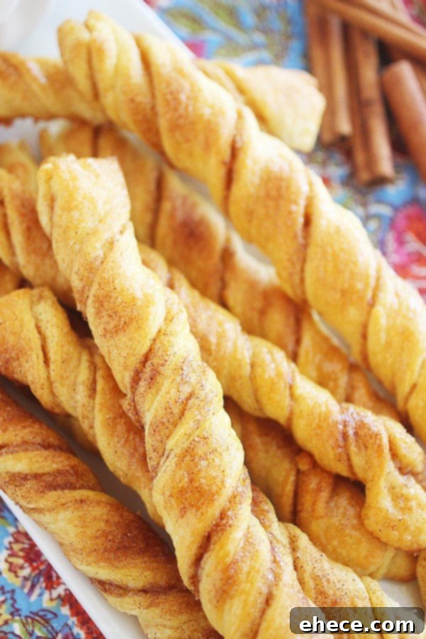 Hands dipping a Cinnamon Roll Twist into a sweet glaze.