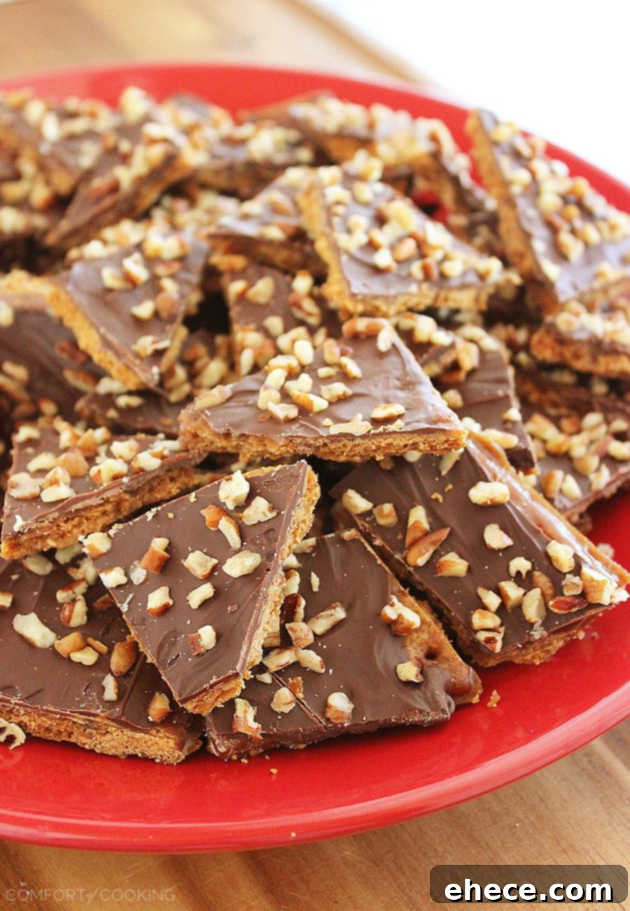A stack of delicious homemade Graham Cracker Toffee pieces on a white plate, showcasing the layers of graham cracker, toffee, chocolate, and nuts.