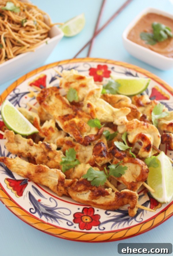 Coconut Ginger Chicken Satay with Sriracha Cream 2 Delicious Coconut-Ginger Chicken Satay skewers with a rich Sriracha dipping sauce on a white plate, garnished with fresh lime wedges.