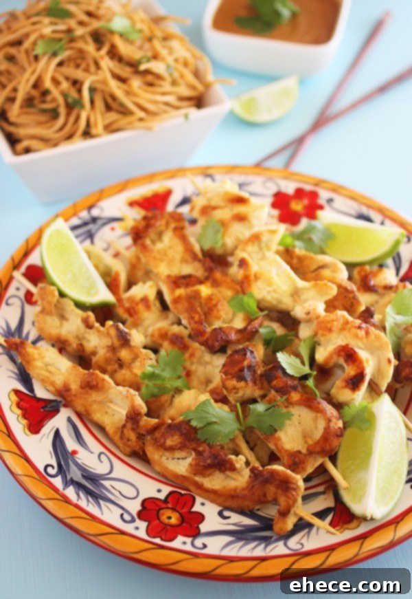 Coconut Ginger Chicken Satay with Sriracha Cream 4 Exquisite presentation of multiple chicken satay skewers, alongside a bowl of Sriracha sauce, lime slices, and fresh cilantro.