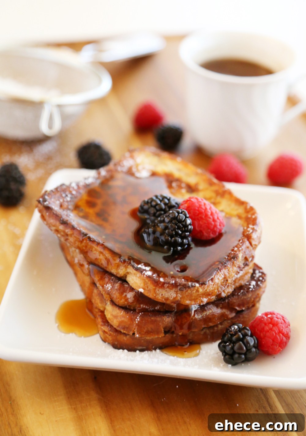 Stack of golden Cinnamon Swirl French Toast with fresh berries and maple syrup, ready for an indulgent breakfast.