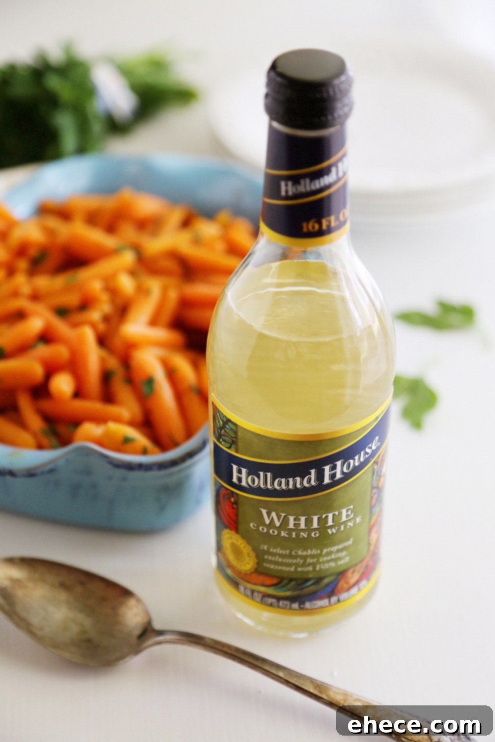 A dish of perfectly glazed baby carrots, garnished with fresh parsley, ready to be served.