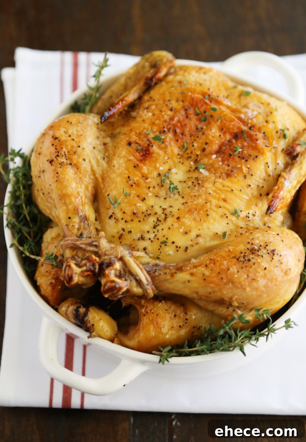 A serving platter with carved Thomas Keller roasted chicken and fresh thyme garnish