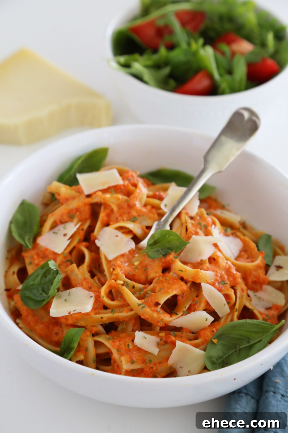 Velvety Roasted Red Pepper Pasta 2 A beautifully presented bowl of creamy roasted red pepper pasta, garnished with fresh basil leaves and a sprinkle of Parmesan cheese.