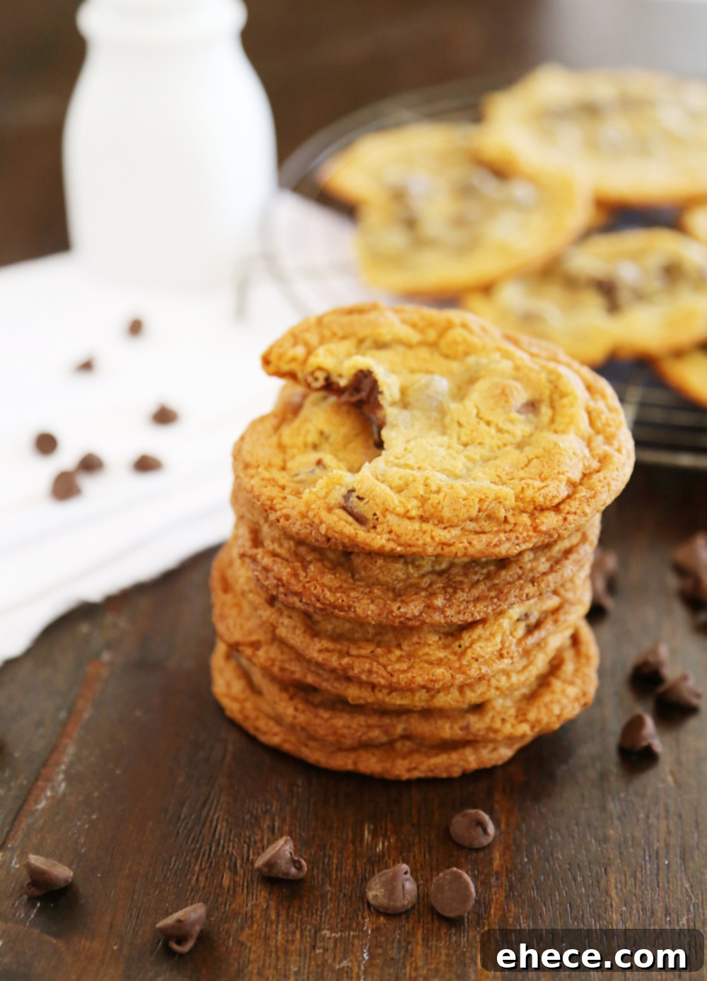 Hand reaching for a thin and chewy chocolate chip cookie from a plate. TheComfortofCooking.com