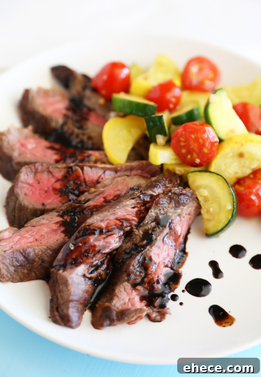 Overhead view of a prepared dish featuring Skillet Balsamic Skirt Steak with colorful zucchini, squash, and cherry tomatoes, beautifully plated.