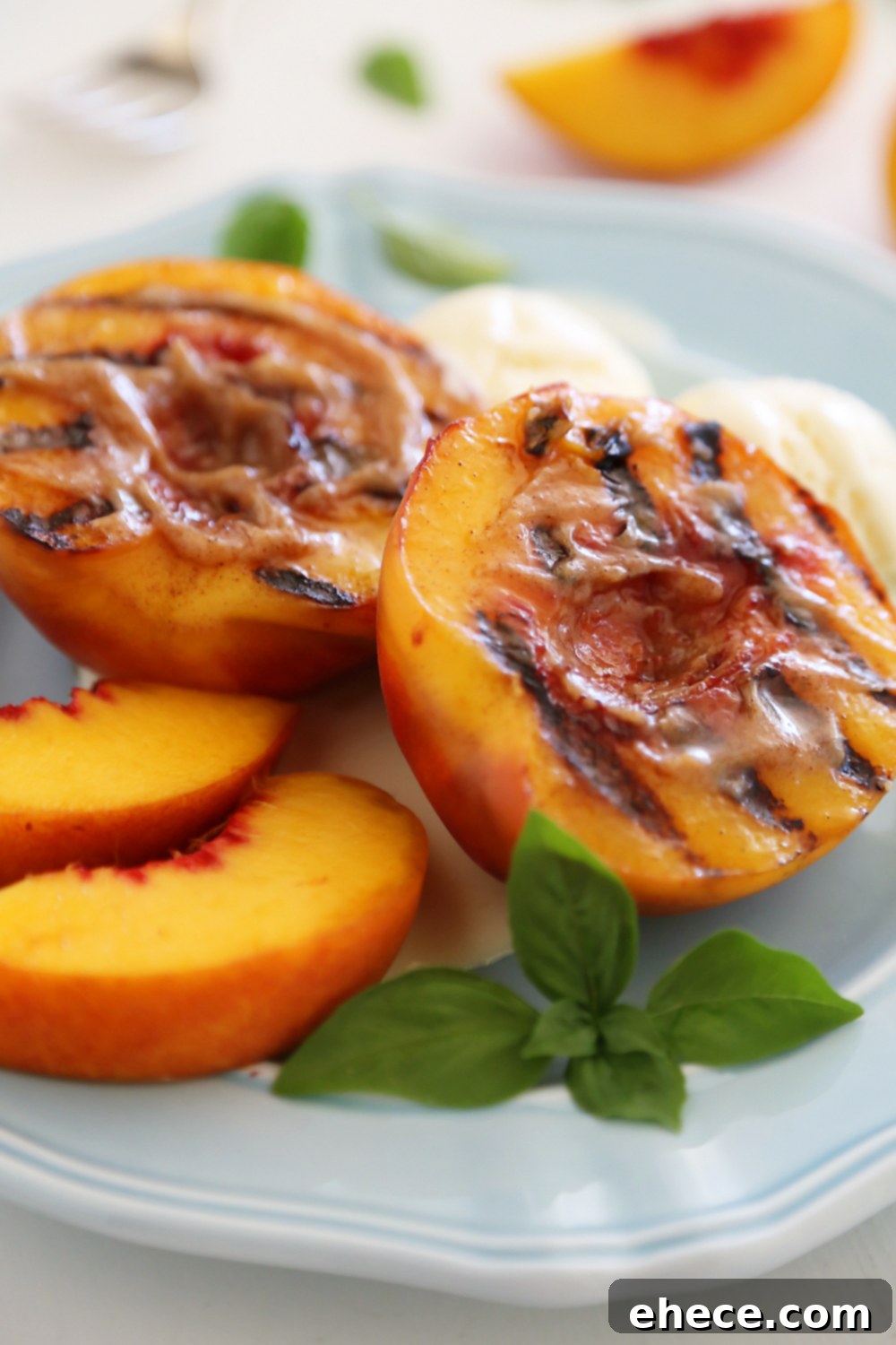 Three grilled peach halves elegantly arranged on a serving plate, drizzled with cinnamon-sugar butter and garnished with fresh herbs, ready for a scoop of ice cream.
